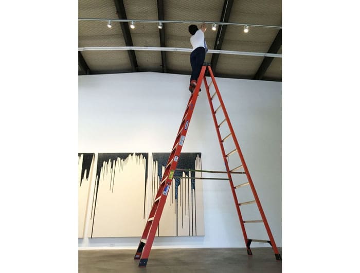 The gallerist, Miz Cluley, tweaks the bright lights before the show. 