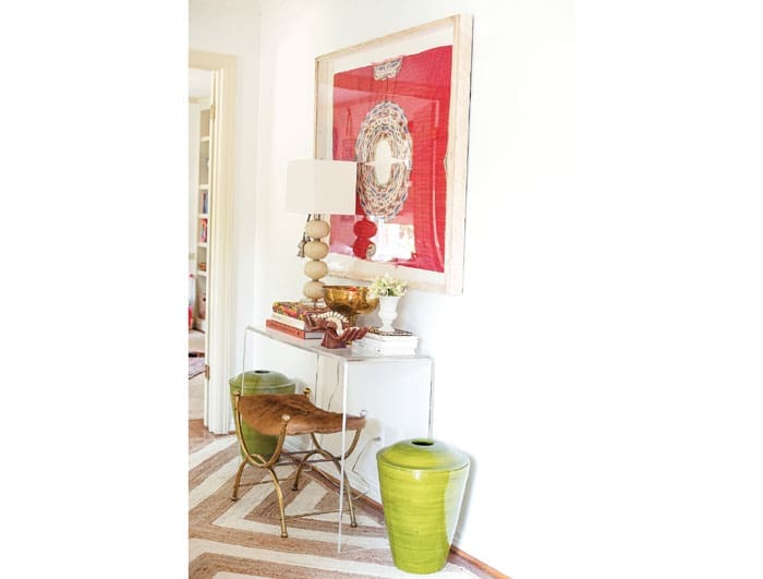 In the entry, a West Elm chevron seagrass rug is rugged enough to withstand dog paws when the doorbell rings. Woven huitil, purchased on a trip to Mexico, framed in acrylic. Brass-and-hide vintage bench. CB2 acrylic console. Woven green basket vases from Mecox.