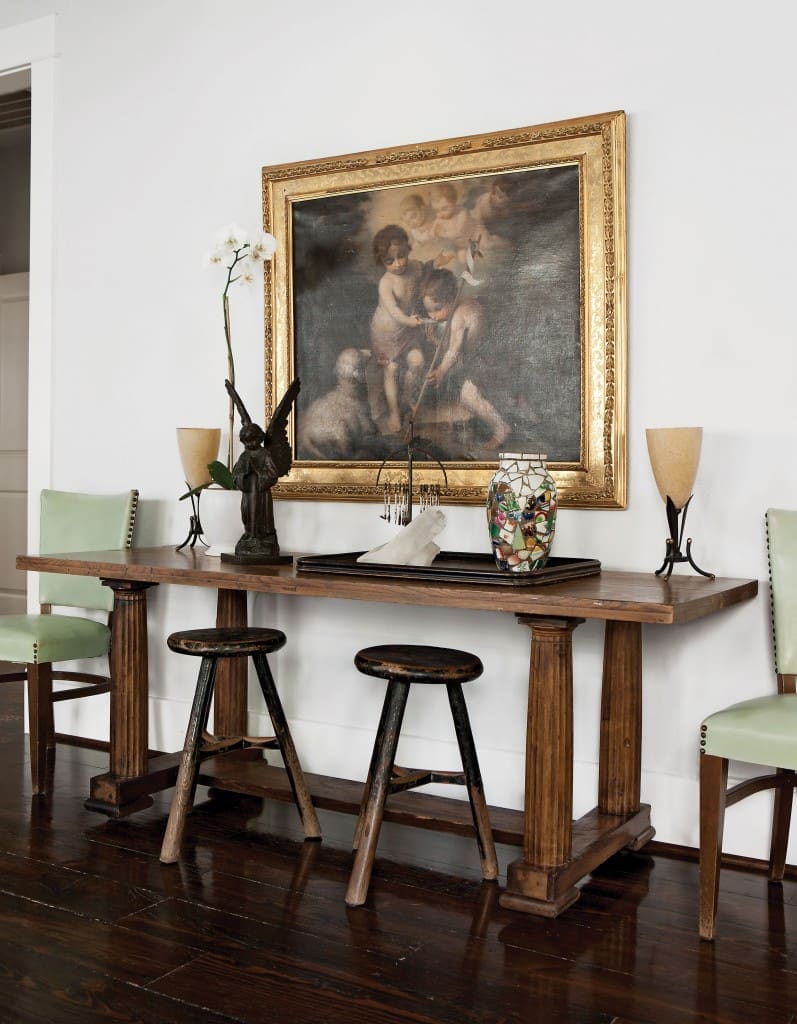 In the dining area, another beguiling mise en scène spans centuries, mixing a grand baroque canvas with a pair of humble stools. Hall table with classical columns gleaned from a
Heights antiquarian. The allegorical painting, a 19th-century reproduction of an earlier master, was literally rescued from a trash bin. Rustic stools from Kuhl-Linscomb, while the upright chairs came from the press room at the Rice Hotel, via an estate sale. Bronze angel from a Brazilian flea market. To its right, a macumba shrine, also from Brazil, where Cusack traveled to visit her mother in the 1980s.