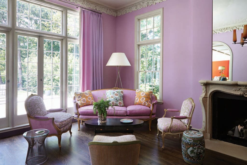 The living room has its original ornate plaster molding and marble fireplace. Inherited Louis XV pieces and antiques from Embree & Lake mix with modern elements, including the husband’s Platner side table.