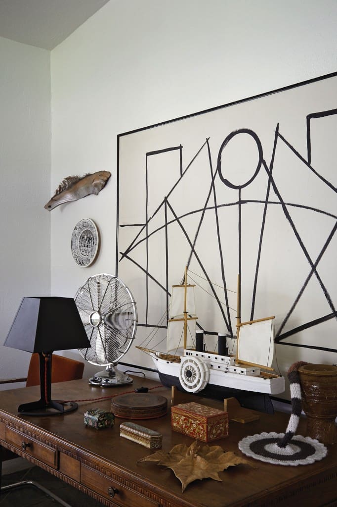 A vintage walnut desk found at a garage sale in St. Louis holds a collection of small treasures.  The model steamship was built by Koush's grandfather.  The black lamp is designed by Alexander Taylor for Established & Sons, from Kuhl Linscomb.  The chrome fan is by Cinni, from Lighting Unlimited.