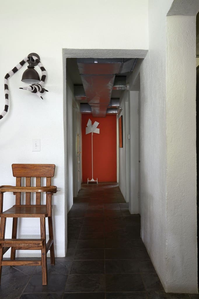 A steel sculpture rescued from a old Galleria-area house being demolished in the late 1990s sits at the far end the hall.  The oak highchair was built by Koush's grandfather and was used by Ben and his brother Greg as children.  The yarn and taxidermy artwork above it is by Houston artist Elaine Bradford.