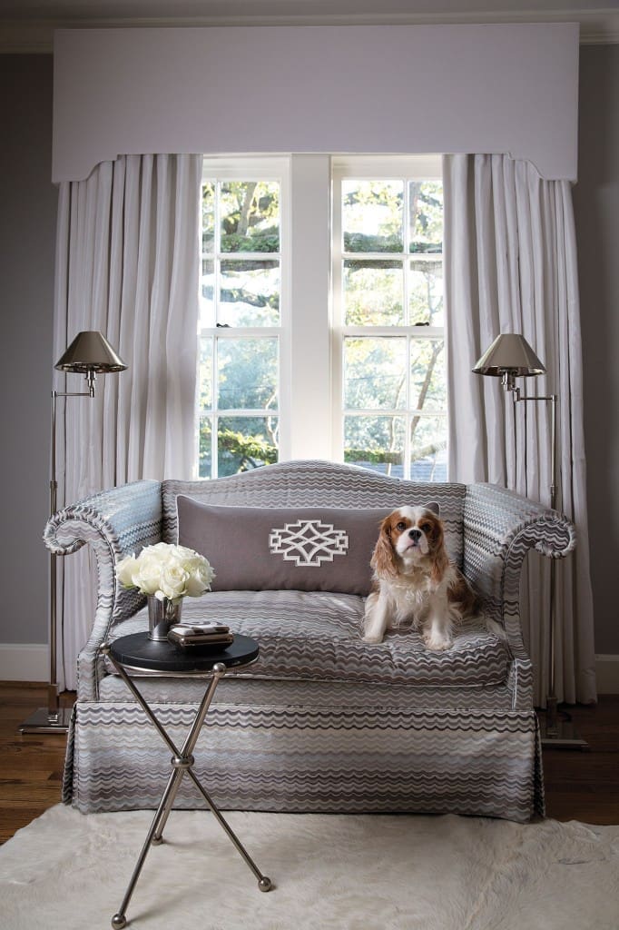 Marni, the family dog, perches on another family heirloom: a petite settee that received a modern update, reupholstered in a silk fabric by Old World Weavers. Black drinks table from Arteriors.
