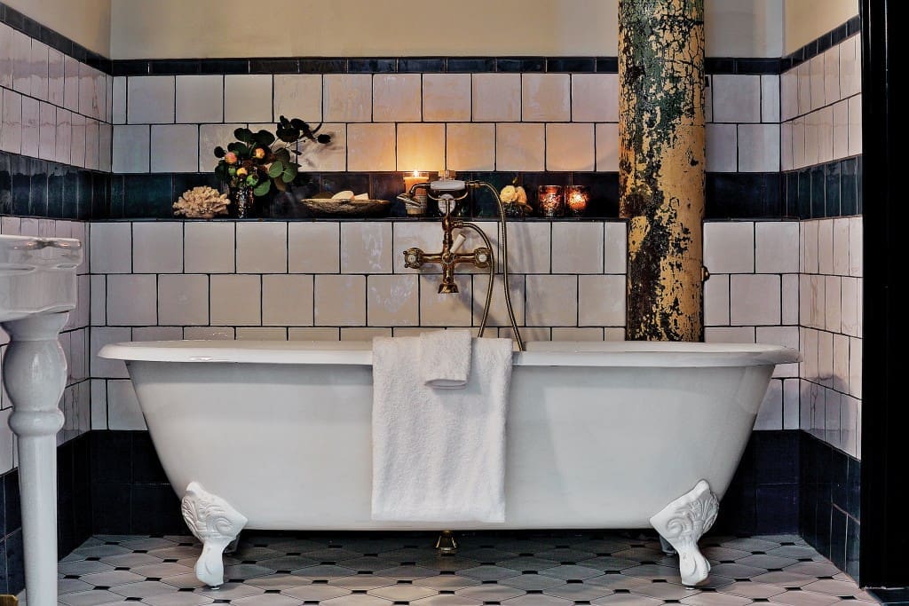 Hotel Emma’s guest bathrooms feature custom blue-and-cream tile with a rustic surface developed by Roman and Williams design firm.