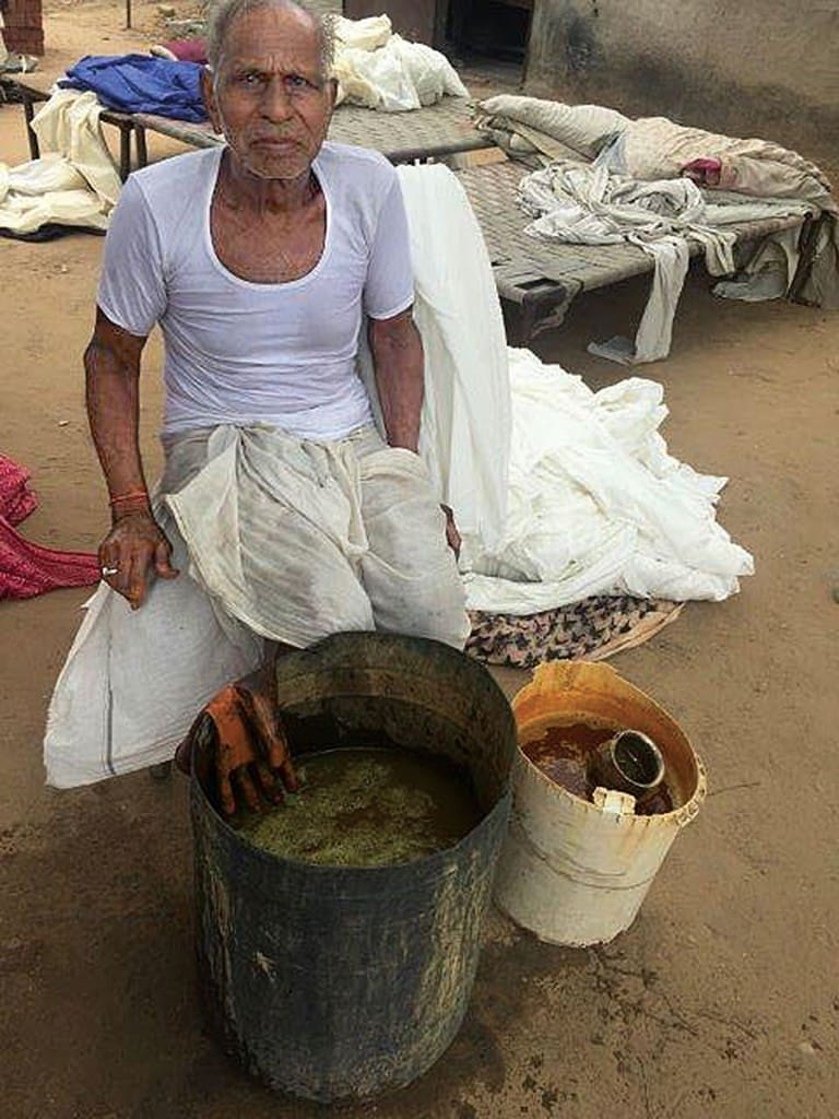 It takes a village: In the printing community of Bagru, India, many artisans play a role in the printing process. Here, one of the expert hand dyers mixes a vat of dye (sometimes using natural dyes from the earth like mustard from flowers, pomegranate or turmeric) to obtain the right shade.