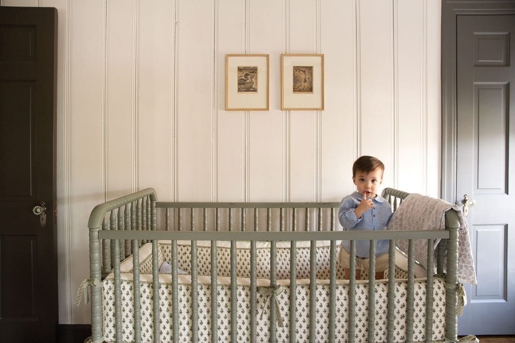 Theo awakes from his morning nap in a Jenny
Lind crib with custom Mela & Roam bedding.
