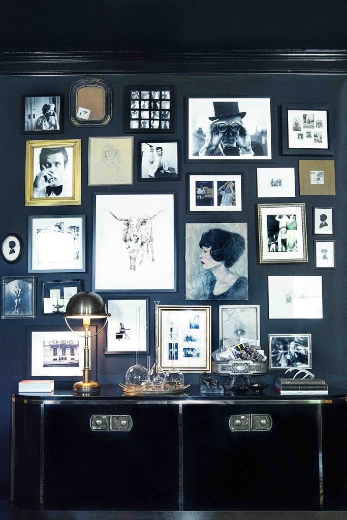 A gallery wall in the library includes Helen Altman's Longhorn torch drawing from Talley Dunn Gallery. Vintage family photos and paintings; vintage Mastercraft Capsule credenza; Ralph Lauren Helmet lamp from Circa Lighting