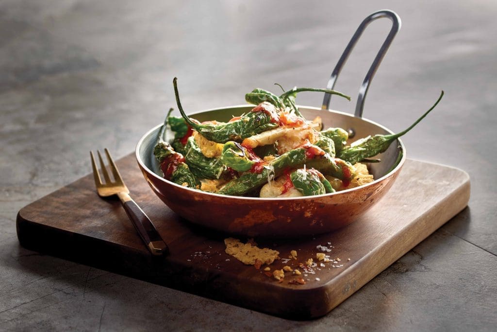 Grotto puts an Italian spin on shisito peppers, tossing them with cauliflower, parmigiana reggiano, and Calabrian chili drizzle. 