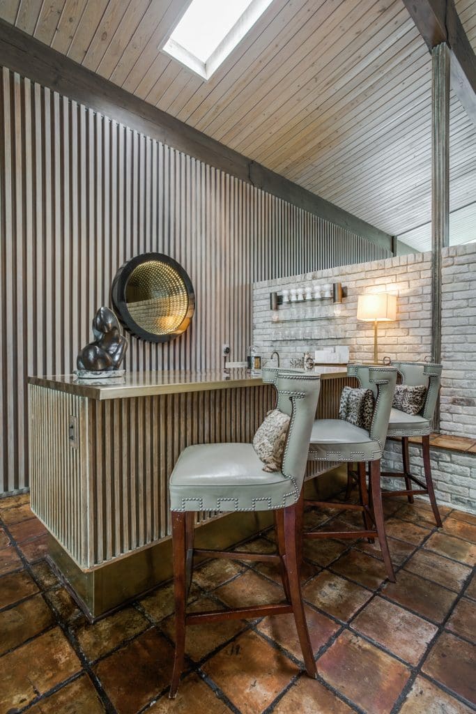 In the bar area off the living room is a restored infinity mirror, circa 1970s, and collection of Swedish glass. The bar top is wrapped in brass.