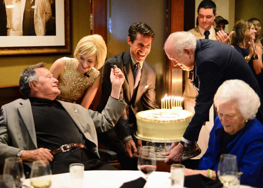 pre-birthday bash as Milton Townsend, left, and Jackson Hicks bring a large carrot cake to the table shared by Barbara Bush. Al Torres photography