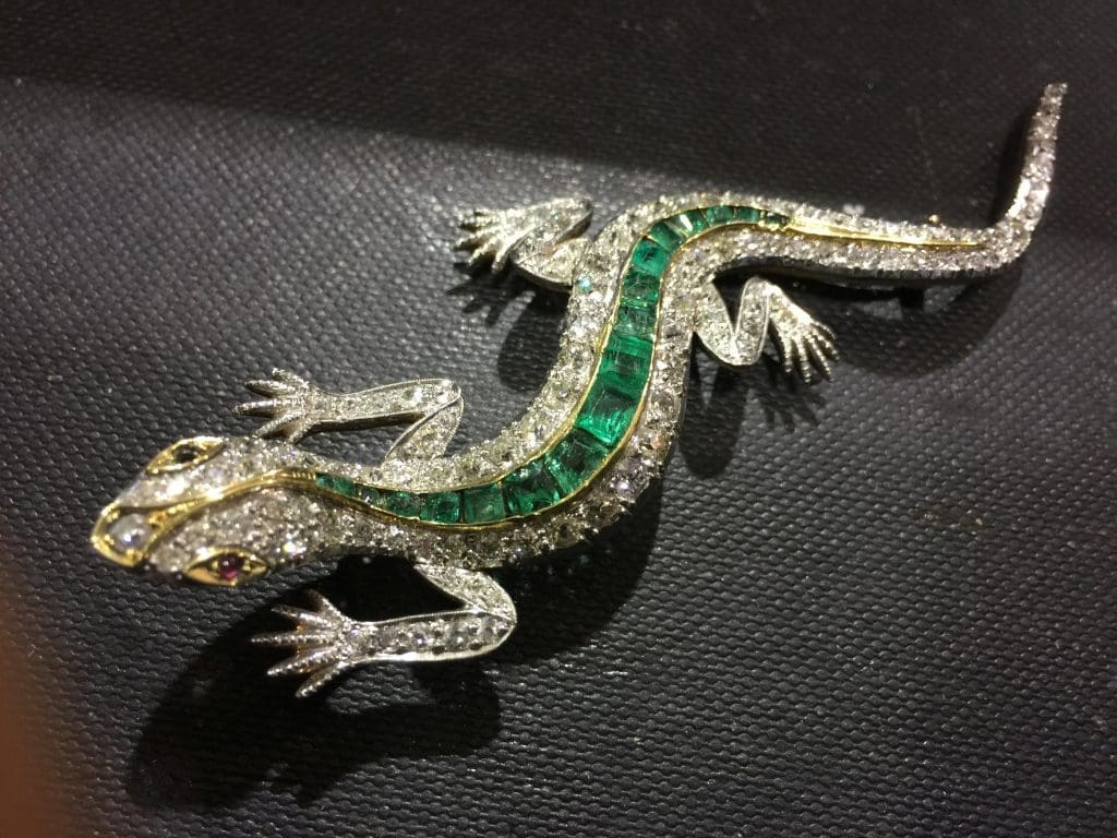 exhibitor Chris Mulloy Antiques of Palm Springs CA showing a lizard pin with Columbian emeralds and diamonds with ruby eyes circa 1870s