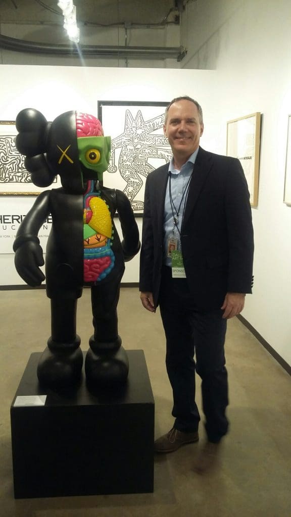 Heritage Auctions' Ed Beardsley converses with a KAWS sculpture set for the auction house's May 22 New York Modern and Contemporary Sale. 