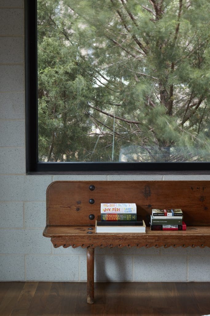 In the master bedroom, 19th-century English railway bench under a large picture window.