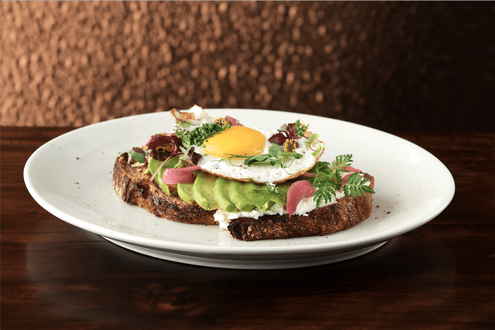 Sourdough toast loaded with avocado, pickled onions, cilantro, and a fried egg. 