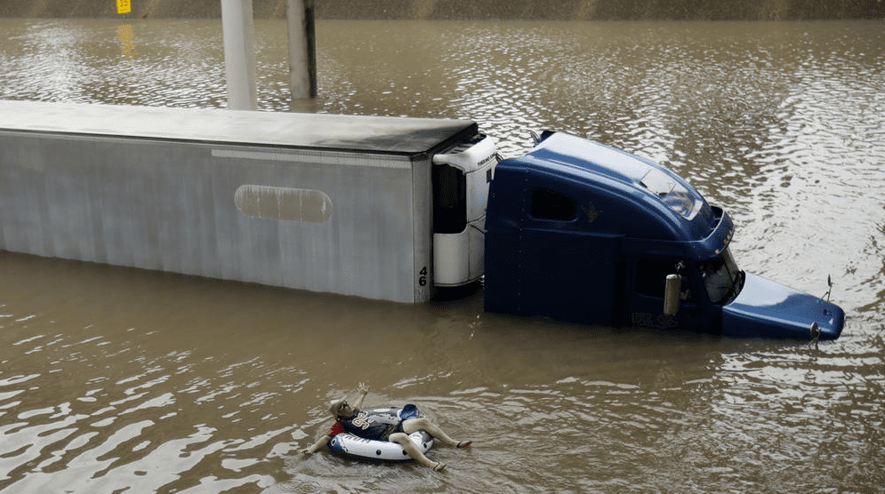 Man floats on the freeway, after helping the driver of a submerged truck escape to safety. (Photo by Charlie Riedel / AP) 