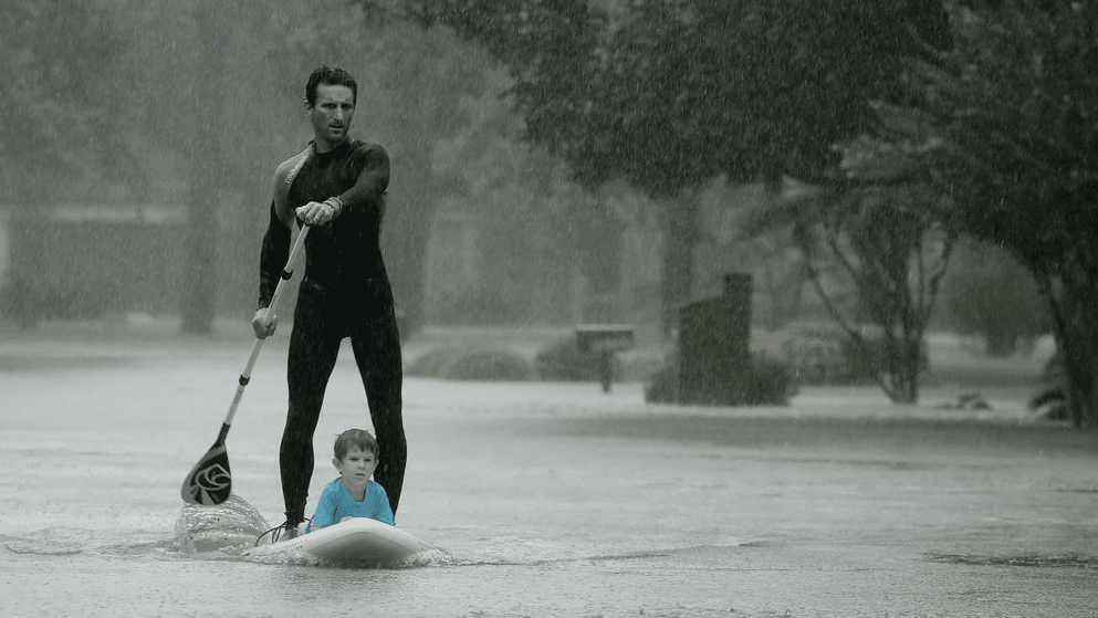 Alexendre Jorge evacuates four-year-old Ethan Colman from flooded neighborhood. (Photo by Charlie Riedel / AP)
