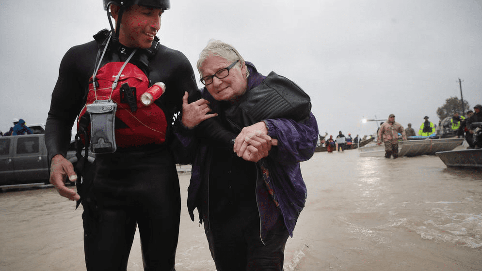 Barb Davis, 74, is helped to dry land after being rescued from her flooded neighborhood. (Photo by Scott Olson / Getty Images)
