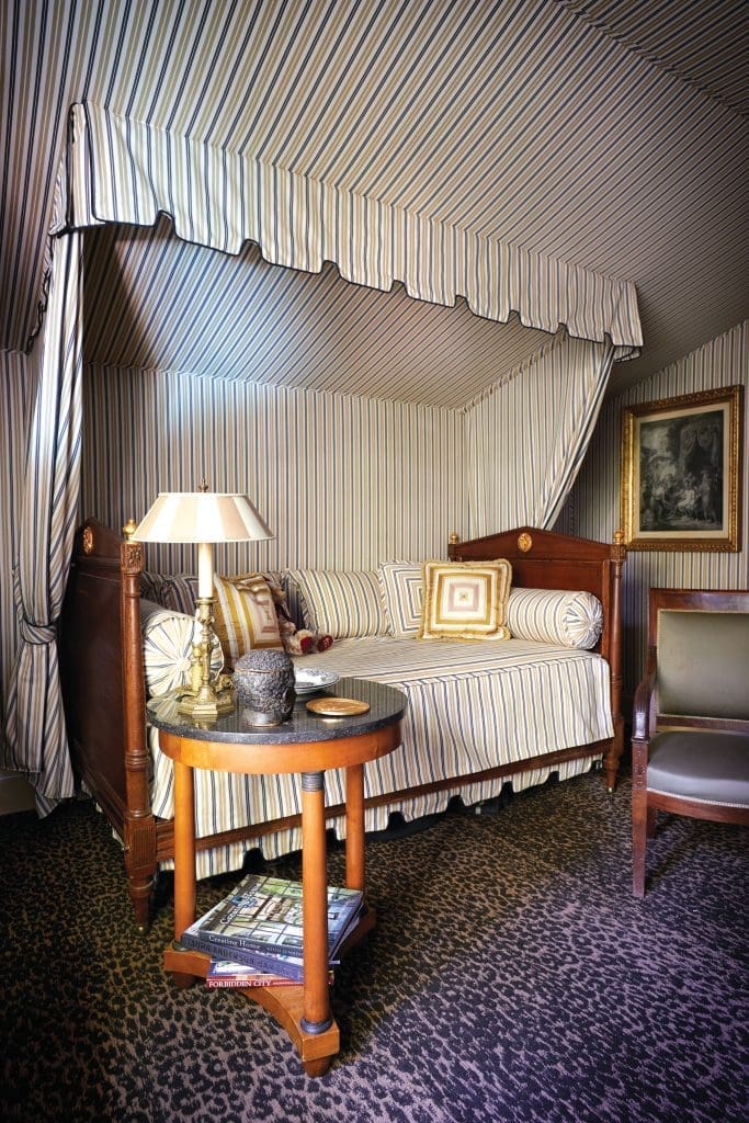 In the guest bedroom, French Directoire daybed with custom linens and wall fabric in cotton mattress ticking. 
