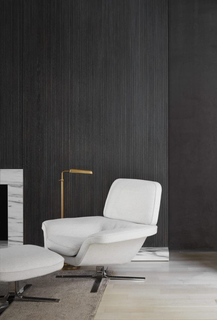 The den’s slatted-wood wall opens to reveal a flat-screen. Statuary-marble fireplace surround. Minotti chair and ottoman.