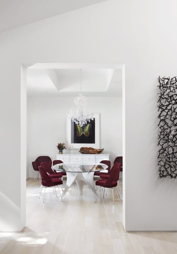 In the dining room, Arc table by Moltini & C from Smink. Knoll Saarinen chairs in red Knoll mohair, from Scott + Cooner. Schonbek chandelier. Butterfly photogravure etching, Damien Hirst’s The Souls on Jacob’s Ladder Take Their Flight, 2007. Wall sculpture is Matt Devine’s The Wake, 2012.