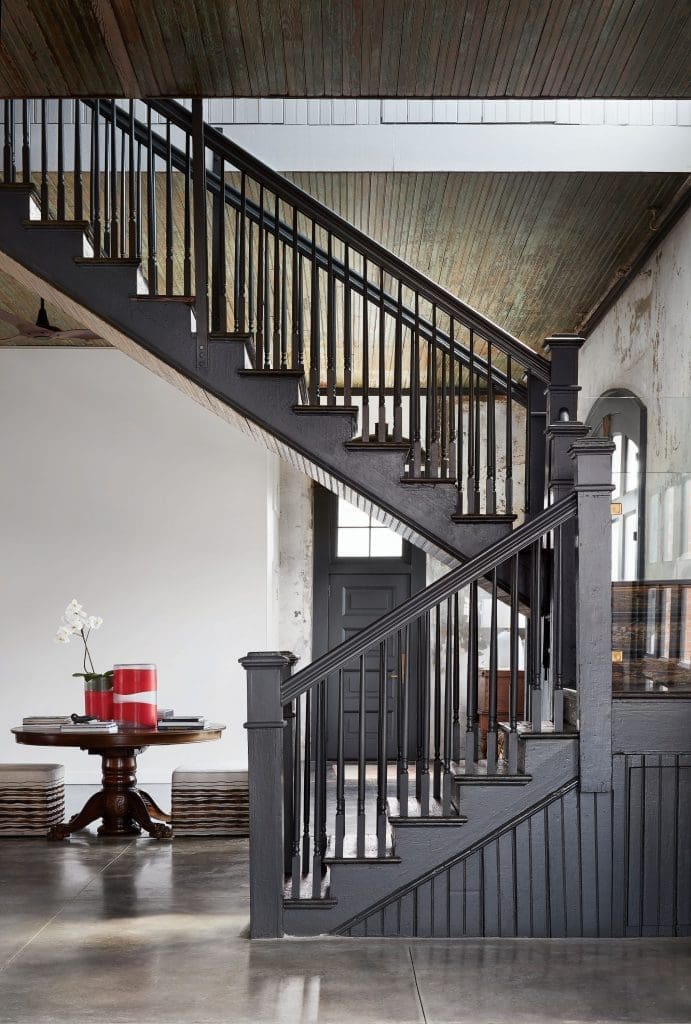 The original staircase has been updated with glass panels on the landing. Original green beadboard ceilings. Red Holly Hunt vases on family heirloom table. Upholstered cubes from Area. 