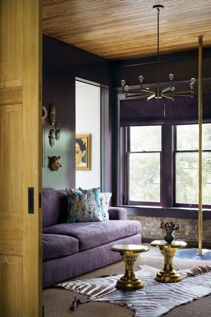 In the library, custom sofa covered in Holly Hunt velvet. Vintage brass tables. African zebra-hide rug. Antique brass fire pole. Vintage painting. 