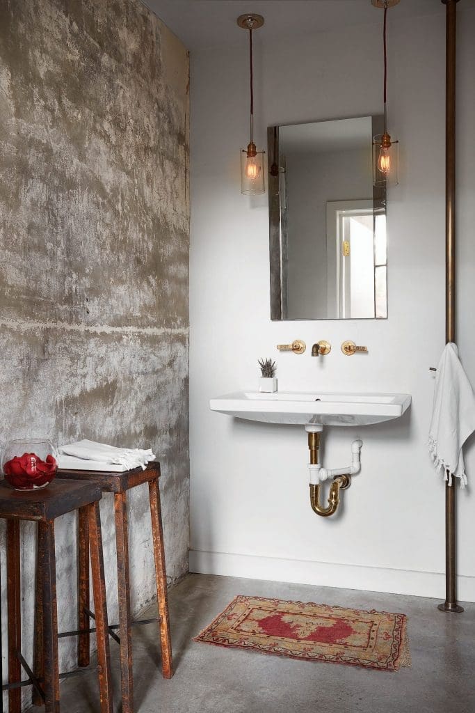 The powder bath's light fixtures hang from red ropes. Brass fire pole made by James Dawson used as towel holder. Antique stools. 