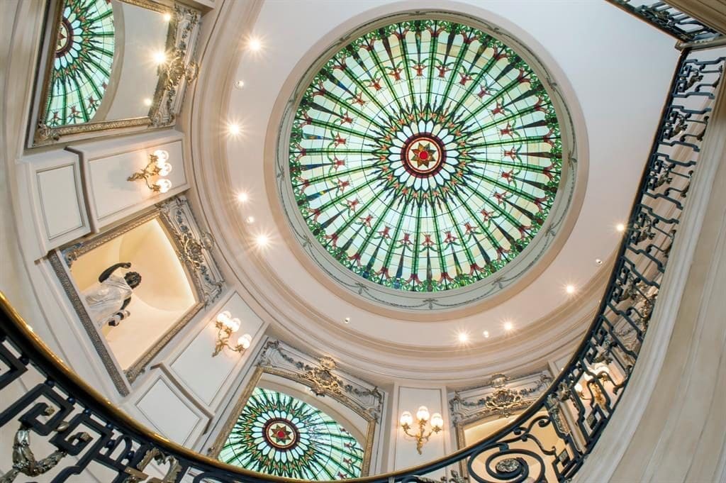 The dramatic stained glass domed ceiling rises above the central staircase at Chateau Cornarvon.