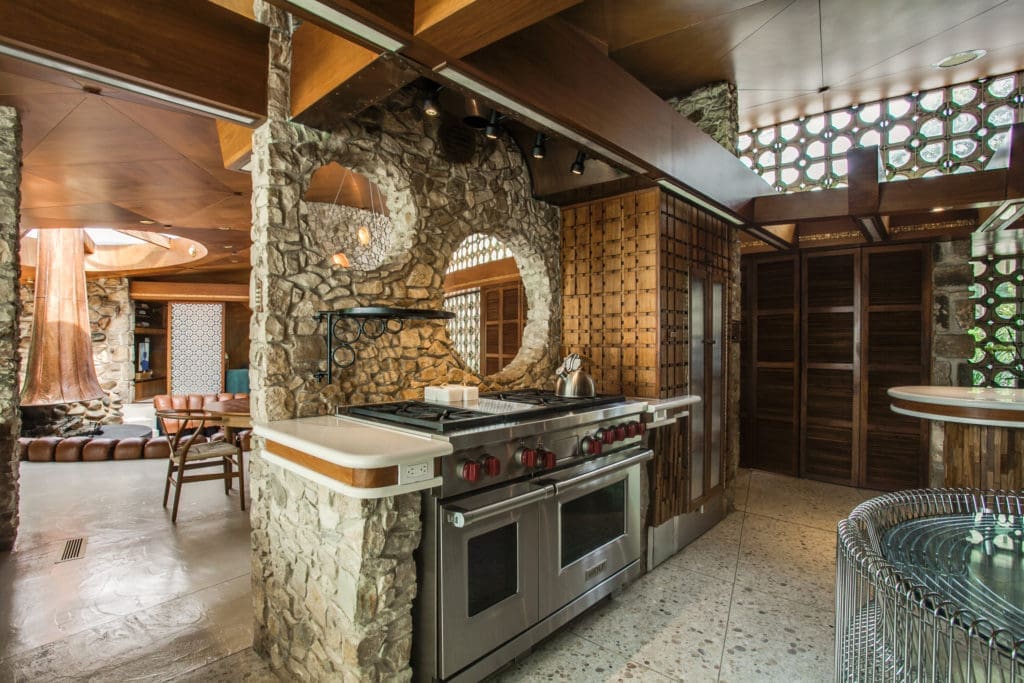 The kitchen features natural stone and walnut paneling.