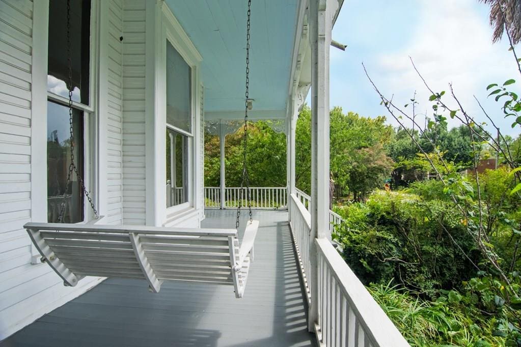 The wrap around porch features traditional paint blue ceilings and a porch swing. 