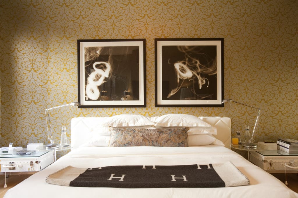 Photographs by Donald Sultan hang above the upholstered platform bed. (Photo by Julie Soefer)