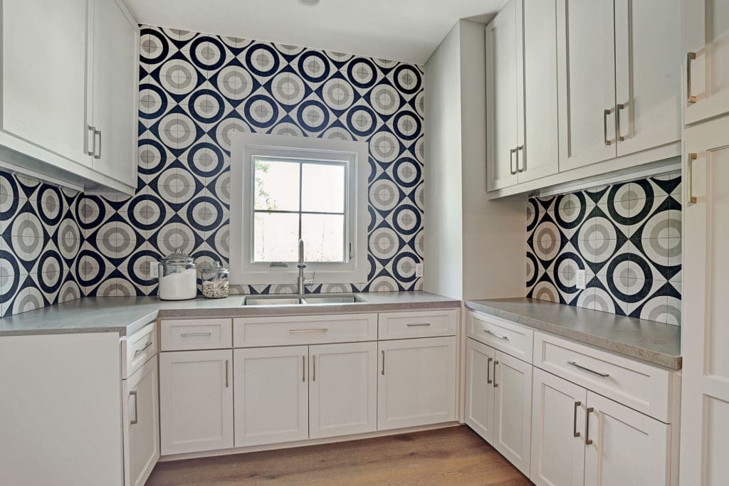 The utility room features designer tile and loads of storage.