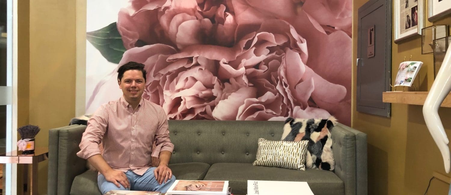 Designer David Peck in his showroom where one of his fabric designs has been translated into a wall mural, one aspect of his latest exercise in creativity.