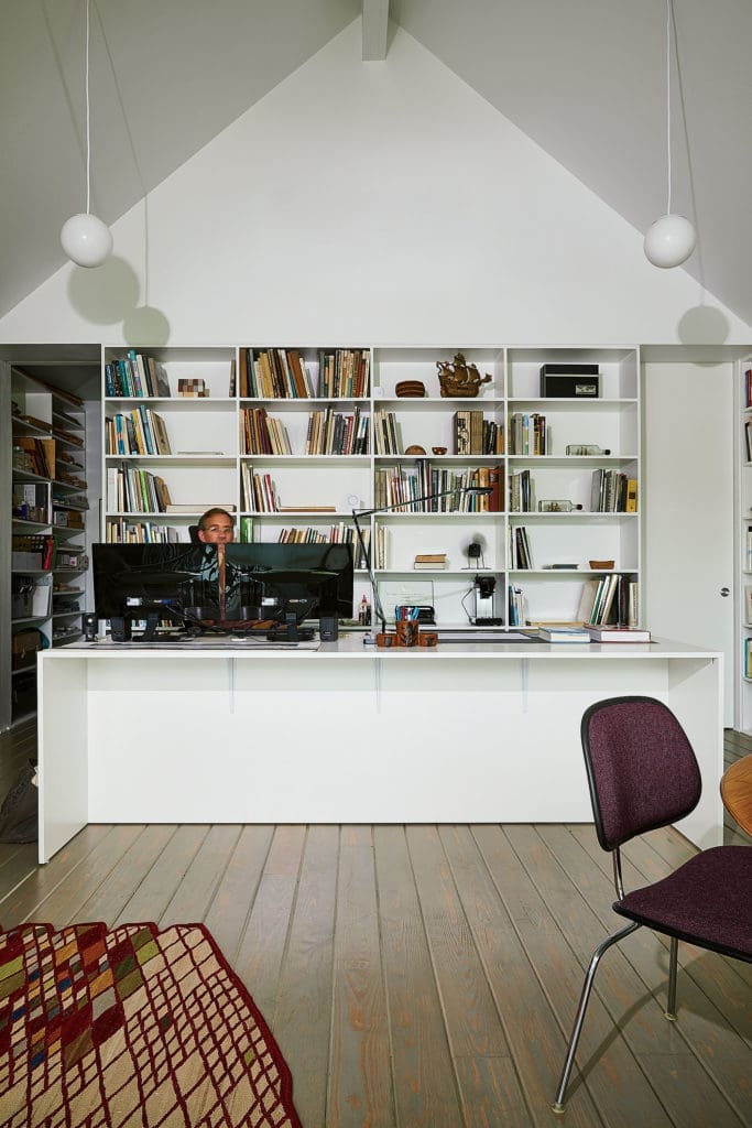 Ben works in his storefront studio at a large melamine table he designed. Kelvin Edge black task lamp was originally designed by Antonio Citterio for Flos in 2015. Ceiling pendants are inexpansive frosted glass globes from Progress Lighting. Lossanges wool carpet was originally designed by the Bouroullec Brothers for Nanimarquina in 2011. Carpet and task lamp from Kuhl-Linscomb. Pencil holder on the desk was made by Ben’s mom for her father. (Photo by Pär Bengtsson)