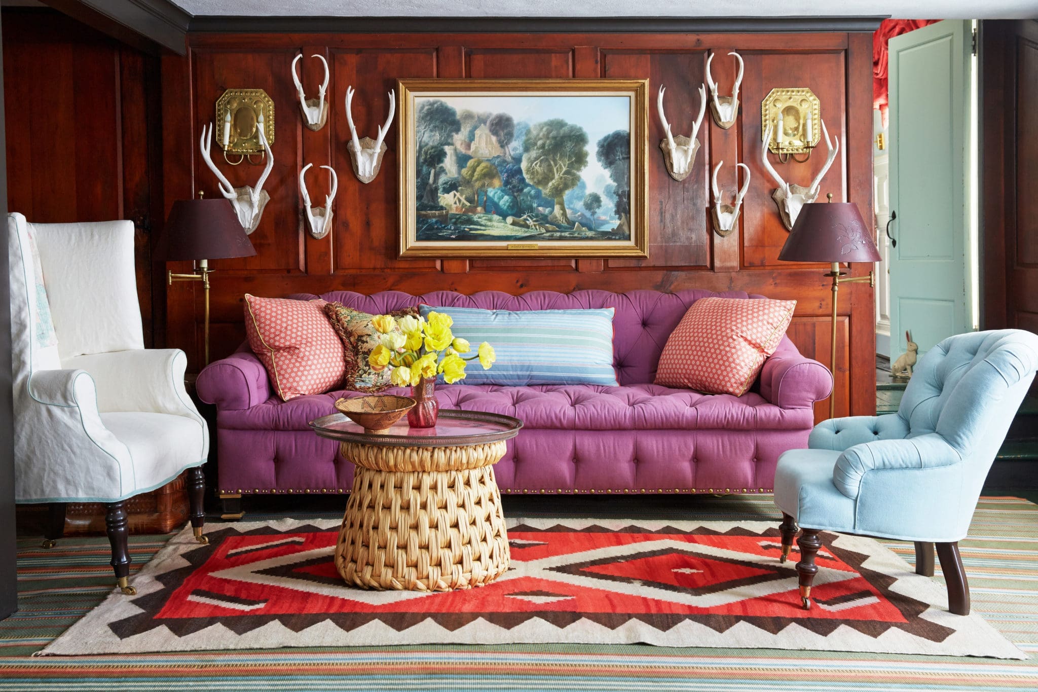 "Pattern is a shortcut to charm, but it's not always my weapon of choice," says Bilhuber. "I'm at my zippiest when pulling colors together." This room is electrified through the mix of the orange in the rug, a blue chair, and a boysenberry tufted sofa.