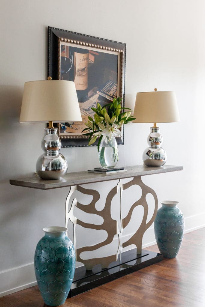The console from Ambella with lamps from Visual Comfort stands across from the wine cellar and leads to the open plan living room. (Photo by Jen Burner)