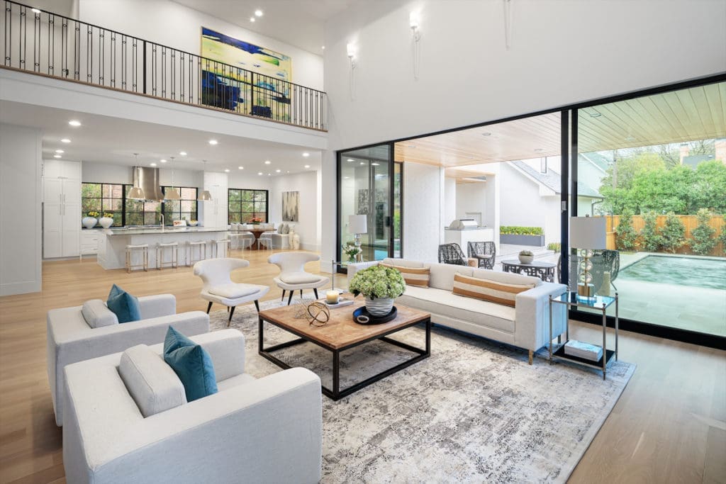 An open living area includes a glass wall that can slide open to reveal a screened-in outdoor living area. 