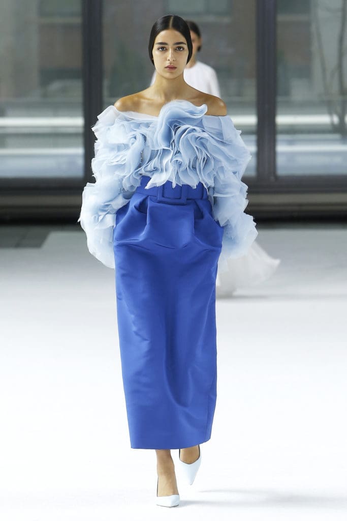Carolina Herrera cornflower blue bias ruffle off-shoulder long sleeve top, tempest blue silk faile tapered skirt, tempest square buckle belt, pale blue pump. (Photo courtesy of Carolina Herrera)