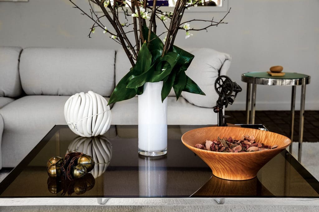 A Walsh tablescape, unchanged since the 1980s, with sleigh bells from her Sioux Falls childhood, a gift to the homeowners, a ceramic sculpture, and turned-wood bowl. Custom side table by Brochsteins. “Sally is very much here,” says Raymond of these interiors. (Photo by Pär Bengtsson)