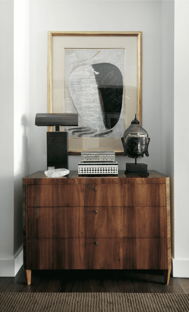 George Cameron Nash, published May 2017. Interior architecture Neal Stewart. Photographed by Lisa Petrole. In the entry hall of George Cameron Nash and Mark Williams' high-rise home, Biedermeier chest, Siamese Buddha, Moroccan inlay boxes, Karl Springer lamp, and a painting purchased in Santa Fe.