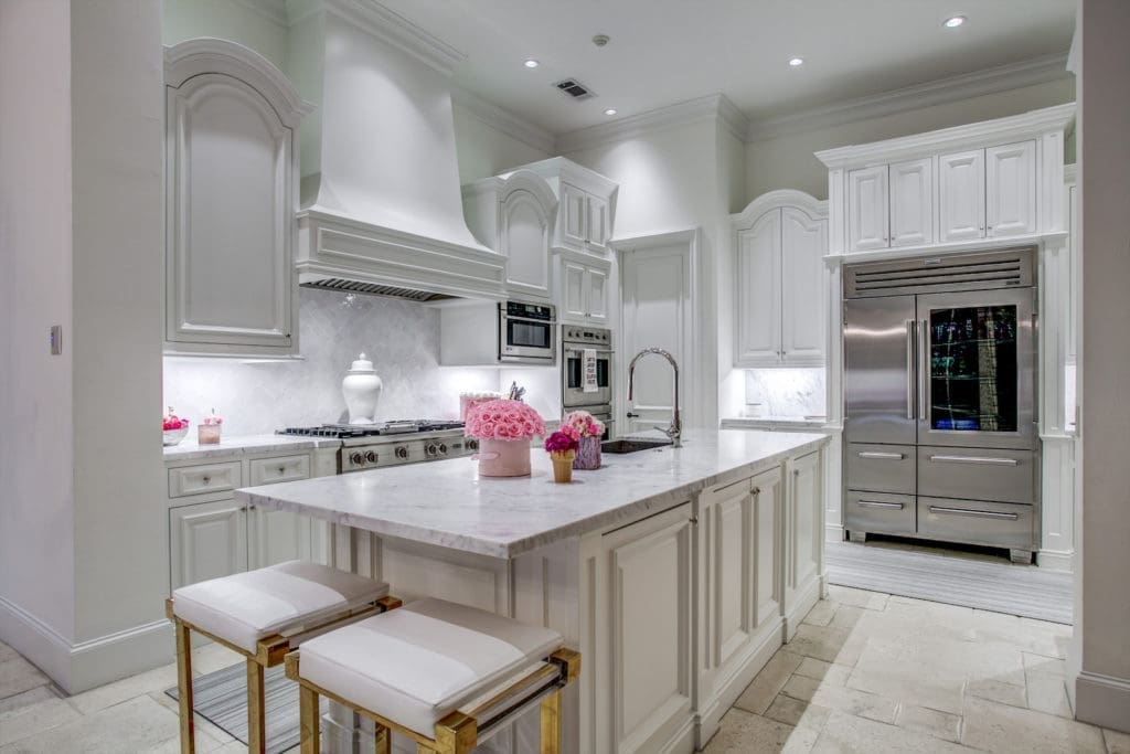 Even in the modern, all-white kitchen, punches of hot pink find their way in. (Photo by Compass Real Estate)