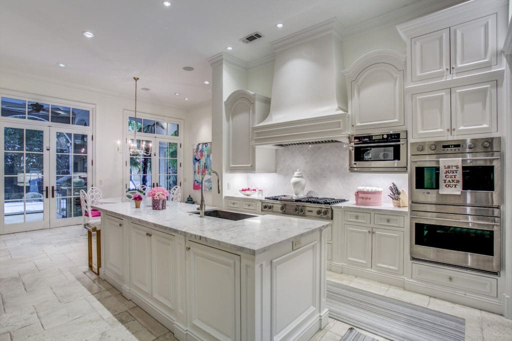 Even in the modern, all-white kitchen, punches of hot pink find their way in.  (Photo by Compass Real Estate)
