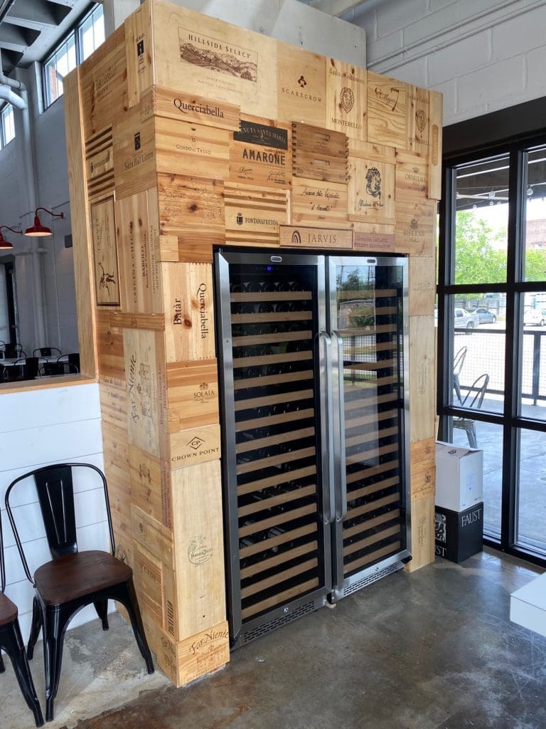 The wine cooler at Porta'Vino is framed in panels from wine boxes. Prices by the bottle only are said to be less than retail across the city. (Photo by Shelby Hodge)