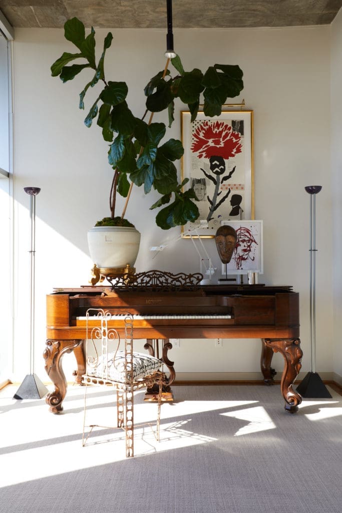 Christopher Alexander experiments with scale and composition in a vignette that includes an antique piano. Vintage Tizio table lamp and a pair of Ron Rezik floor lamps. Large lithograph by Donald Baechler. Small red India ink portrait by South African artist BJ Broekhuizen. Vintage garden chair from Round Top with Fortuny Pillow.  (Photo by Pär Bengtsson)