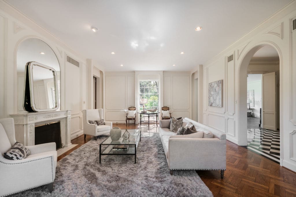 The formal living room features a grand marble fireplace, herringbone hardwood flooring, original triple hung windows, high ceilings and views of gardens. (Photo by Vlady Ambia)