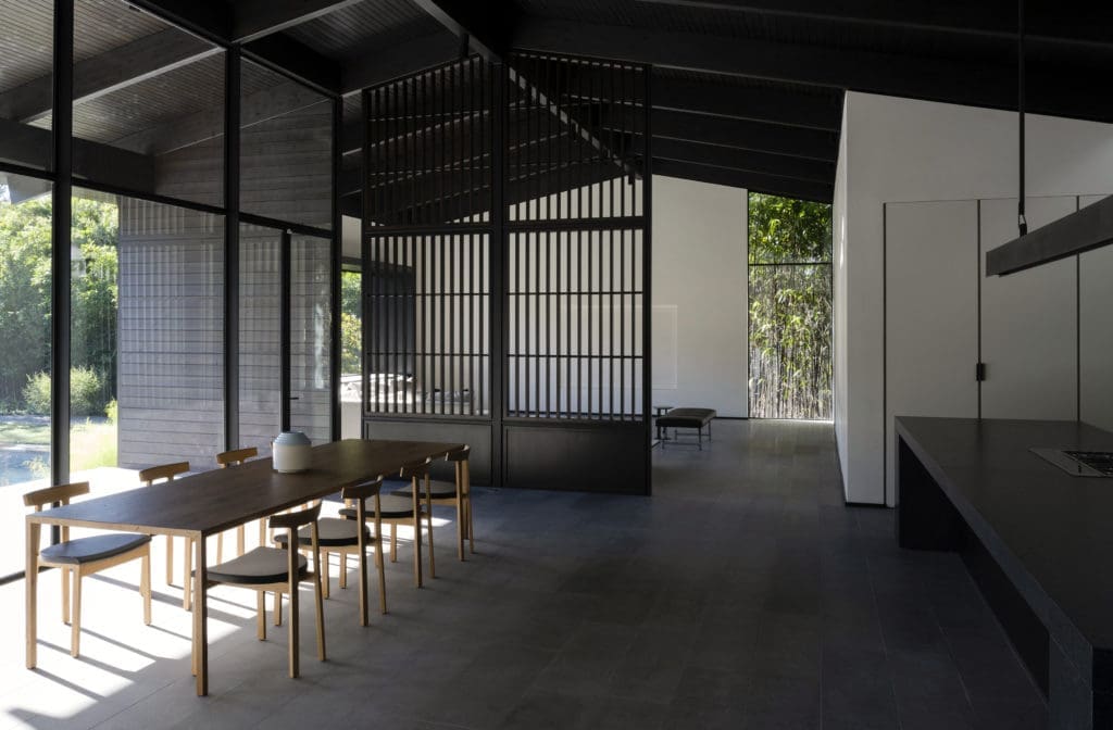 A vertical screen separates the open dining/kitchen expanse from the great room.  (Photo by Jack Thompson Photography)