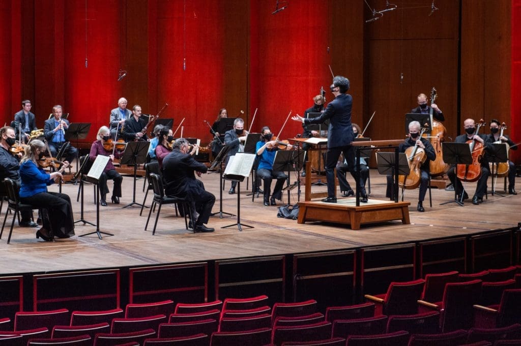 In masks and casual attire, members of the Houston Symphony perform at Jones Hall during the pandemic under direction of Yoonshin Song. (Photo by Wilson Parish)