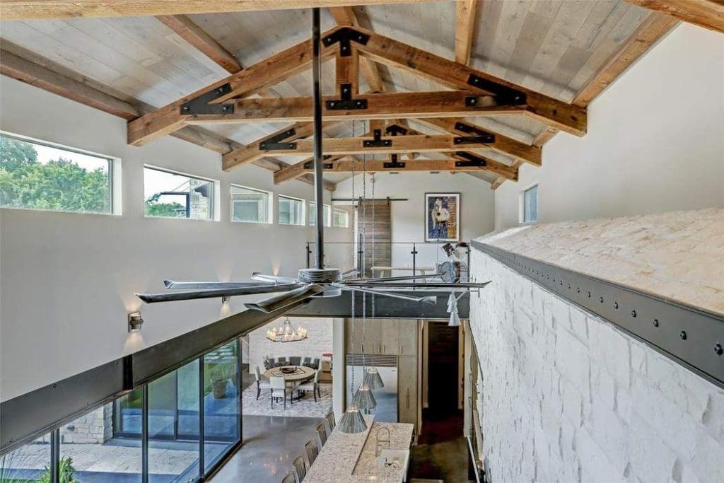 The two-story ceiling is punctuated with exposed beams and joists with iron detailing.