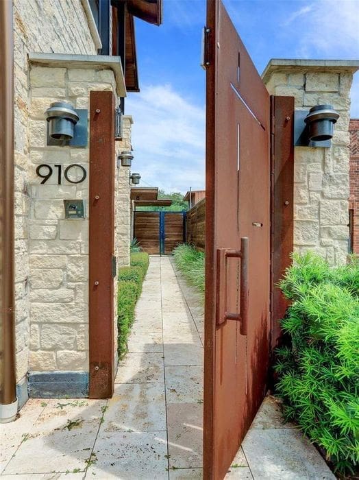 The iron gate opens to a path leading to the house entry.