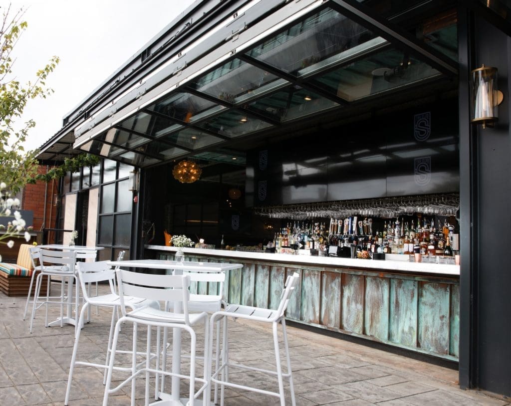 Airline hangar doors at The Sporting Club open to connect the 360-degree marble bar to the outdoor patio. (Photo by Corine Michel )